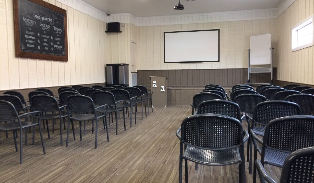 Auditorium-style room with rows of chairs and projector