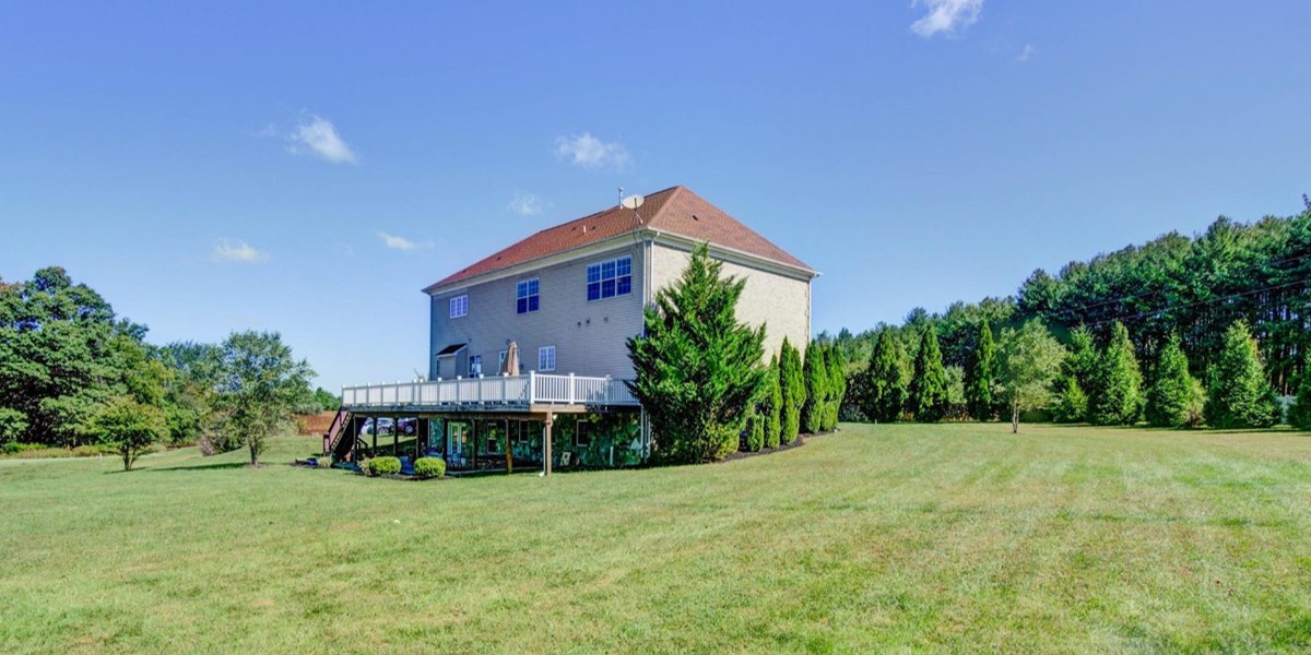 Large brick house with deck and open green lawn