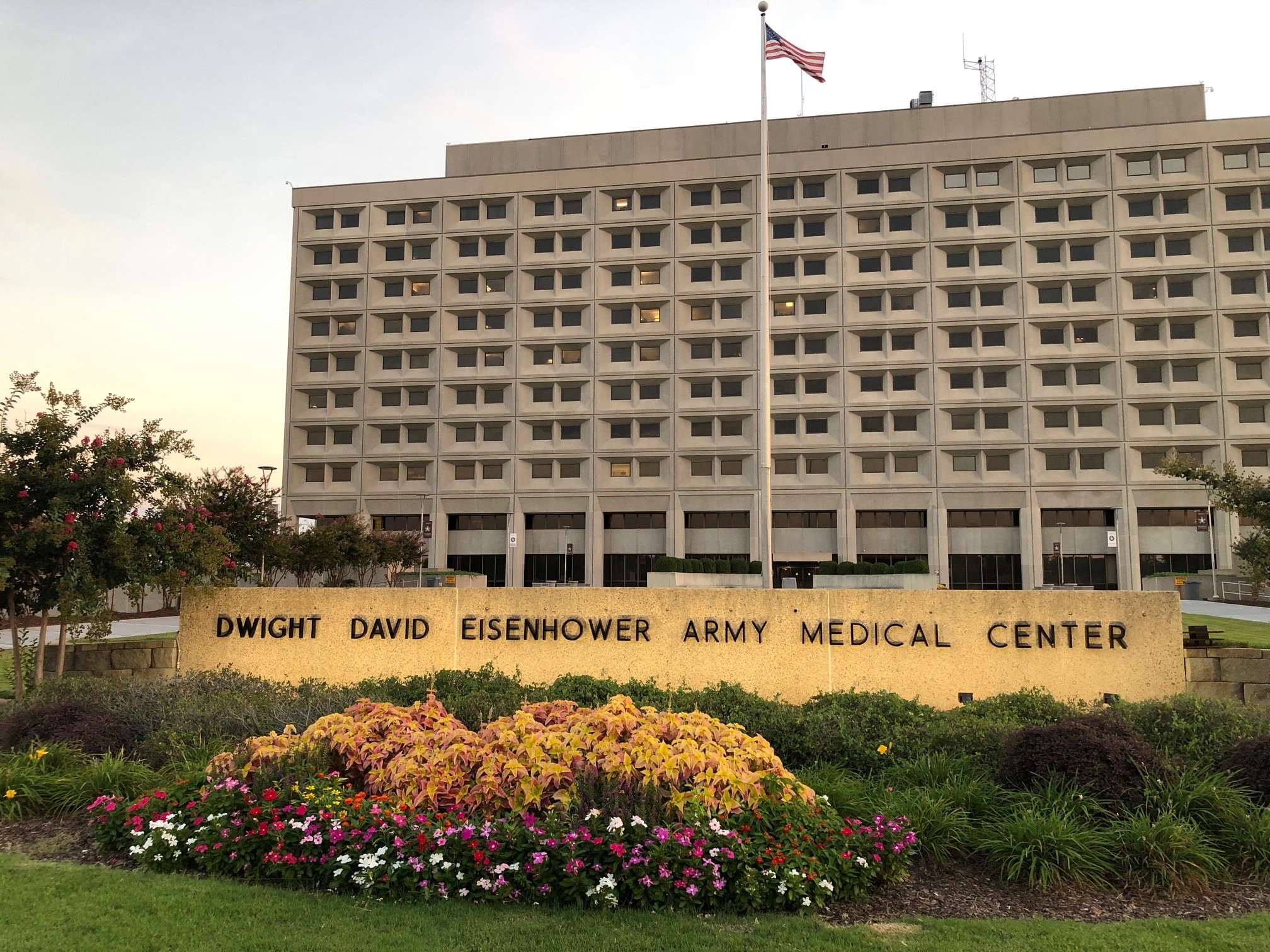 Multi-story medical center with entrance sign and flower garden