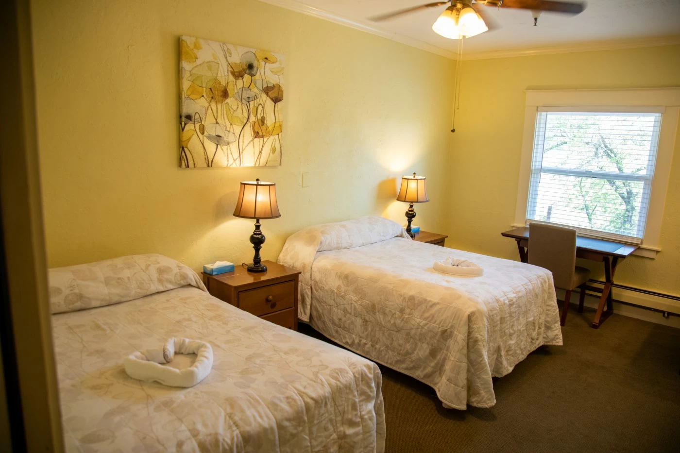 Bedroom with two beds, lamps, and window workspace