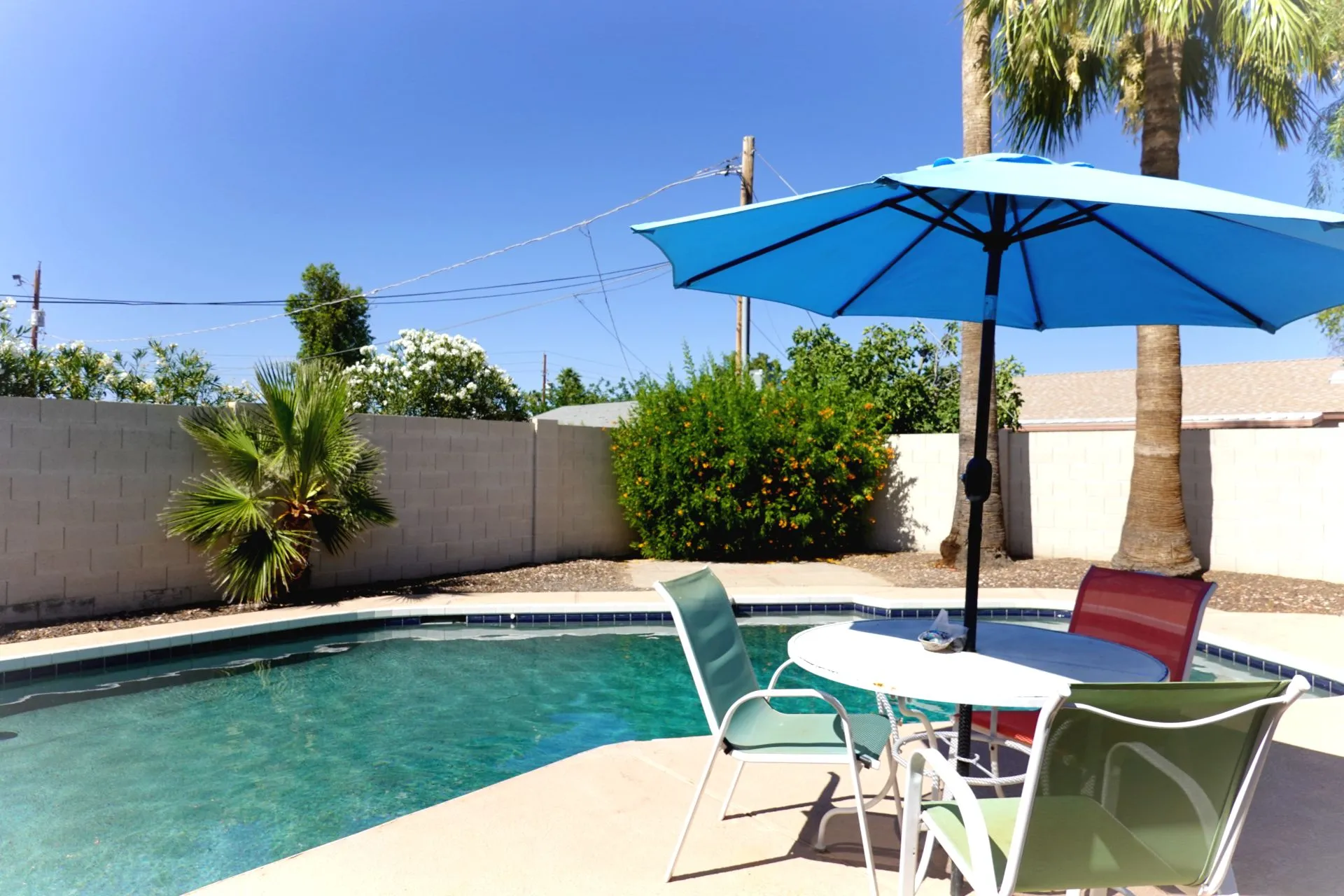Outdoor pool with umbrella, table, and chairs in private backyard