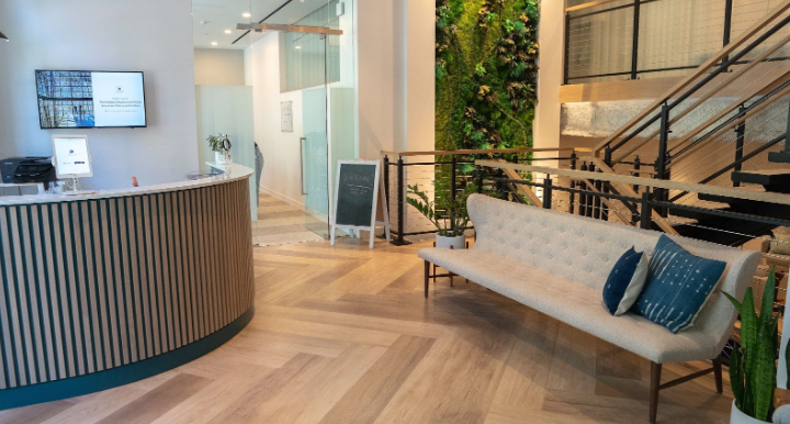 Reception area with front desk, bench, stairs, and plant wall
