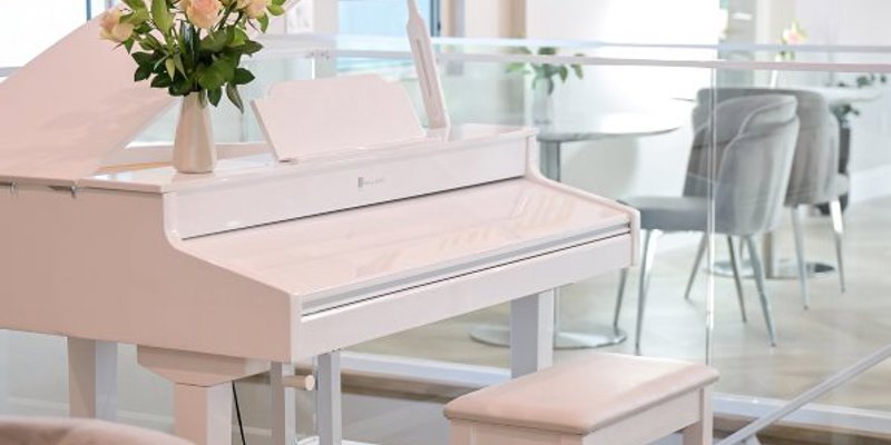  A sleek, white piano adorned with a vase of fresh flowers stands in an elegant, airy space, creating a calming and luxurious ambiance.