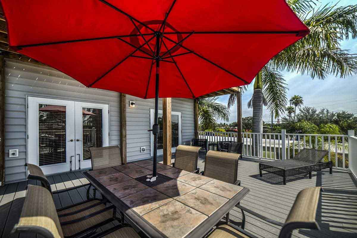 Outdoor dining area with red umbrella and palm trees