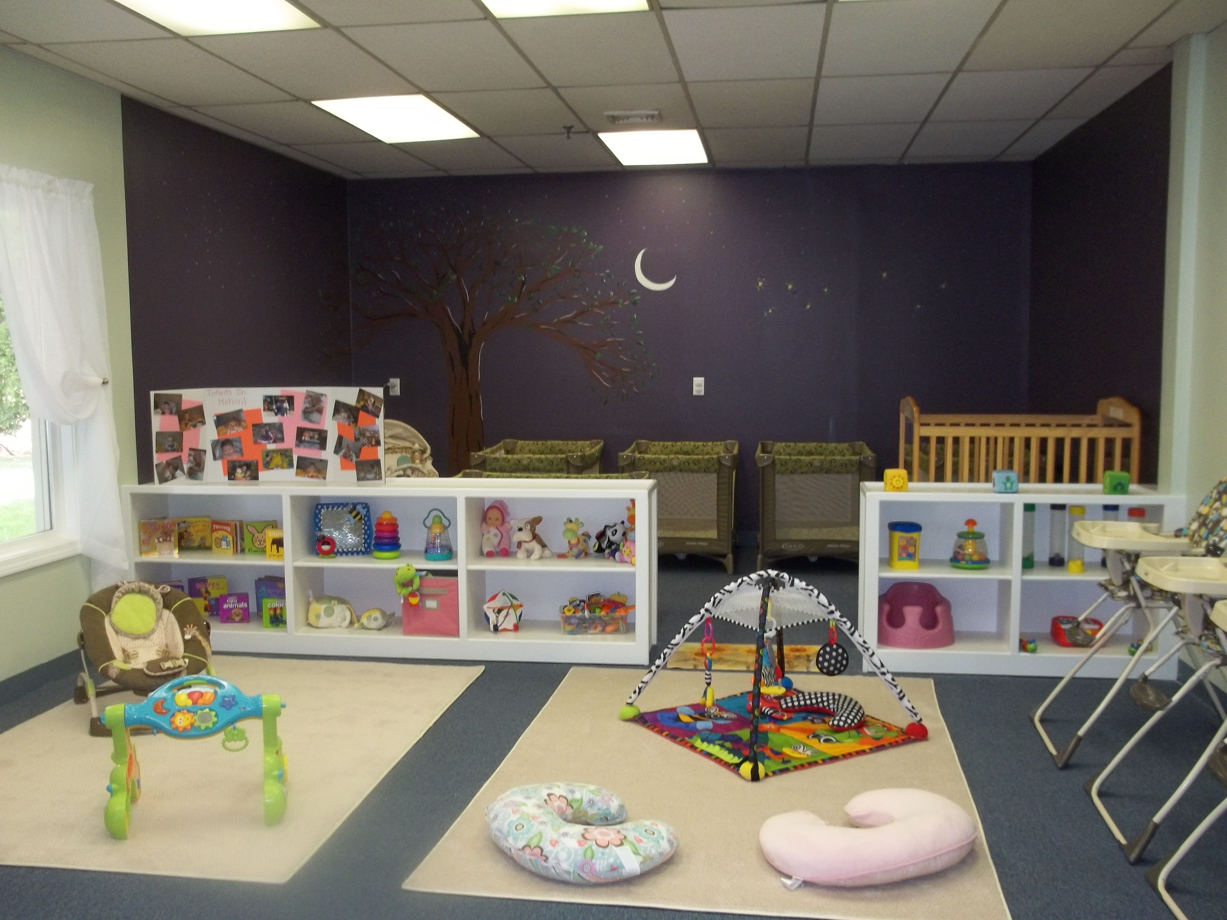 Infant playroom with toys, cribs, and activity mats at Odyssey House.