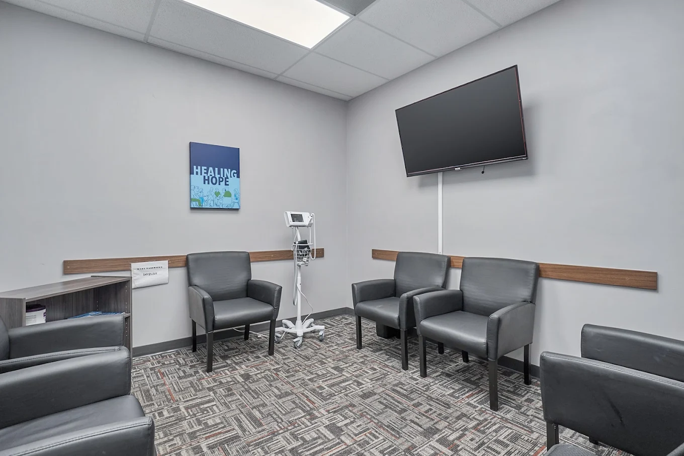 Patient waiting room with chairs, TV, and medical equipment