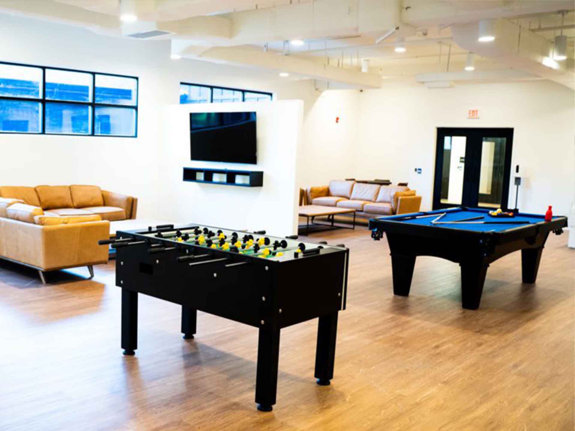 A recreation room with a foosball table, pool table, and seating