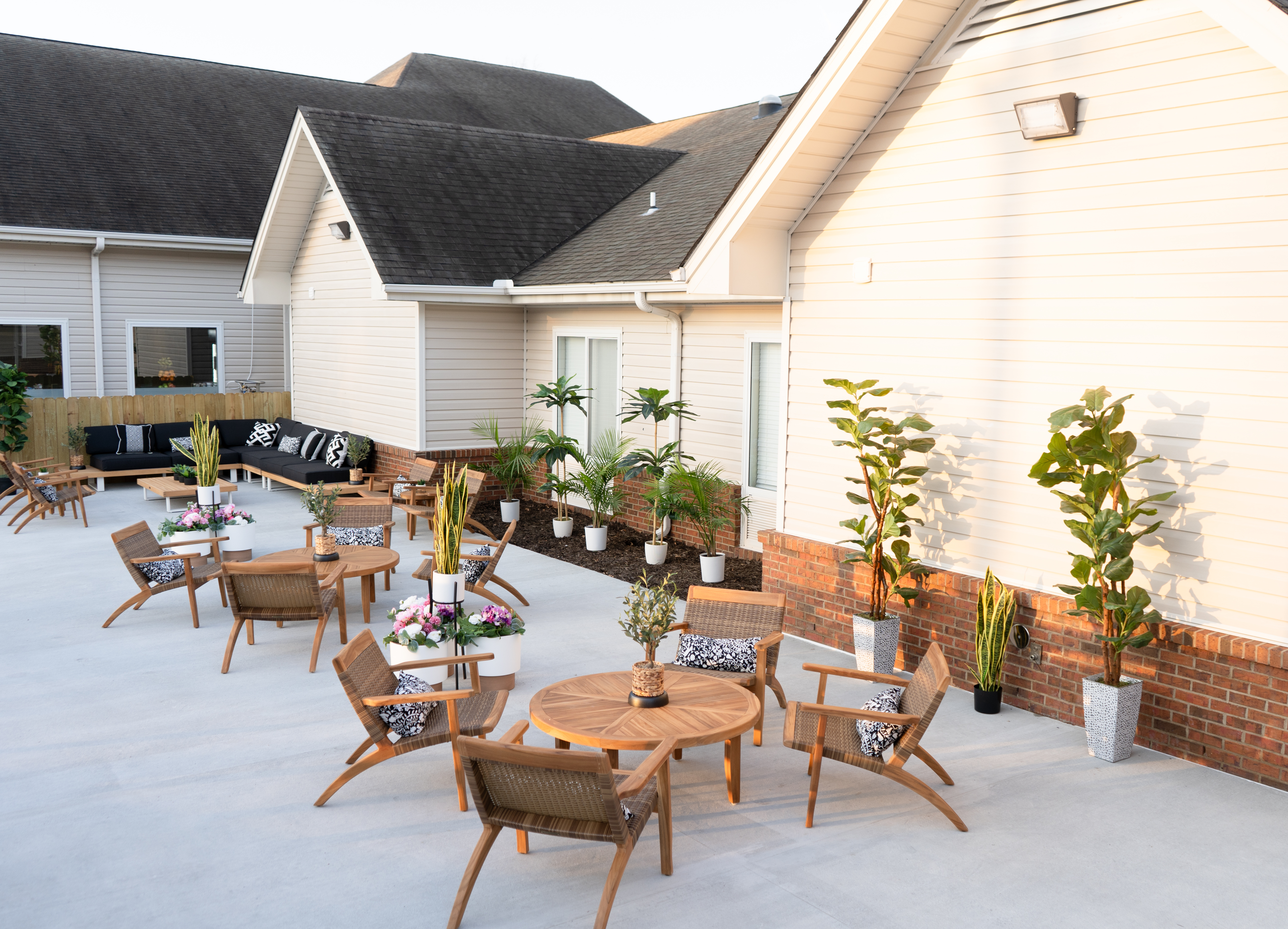 Outdoor patio with wooden tables, chairs, and potted plants.