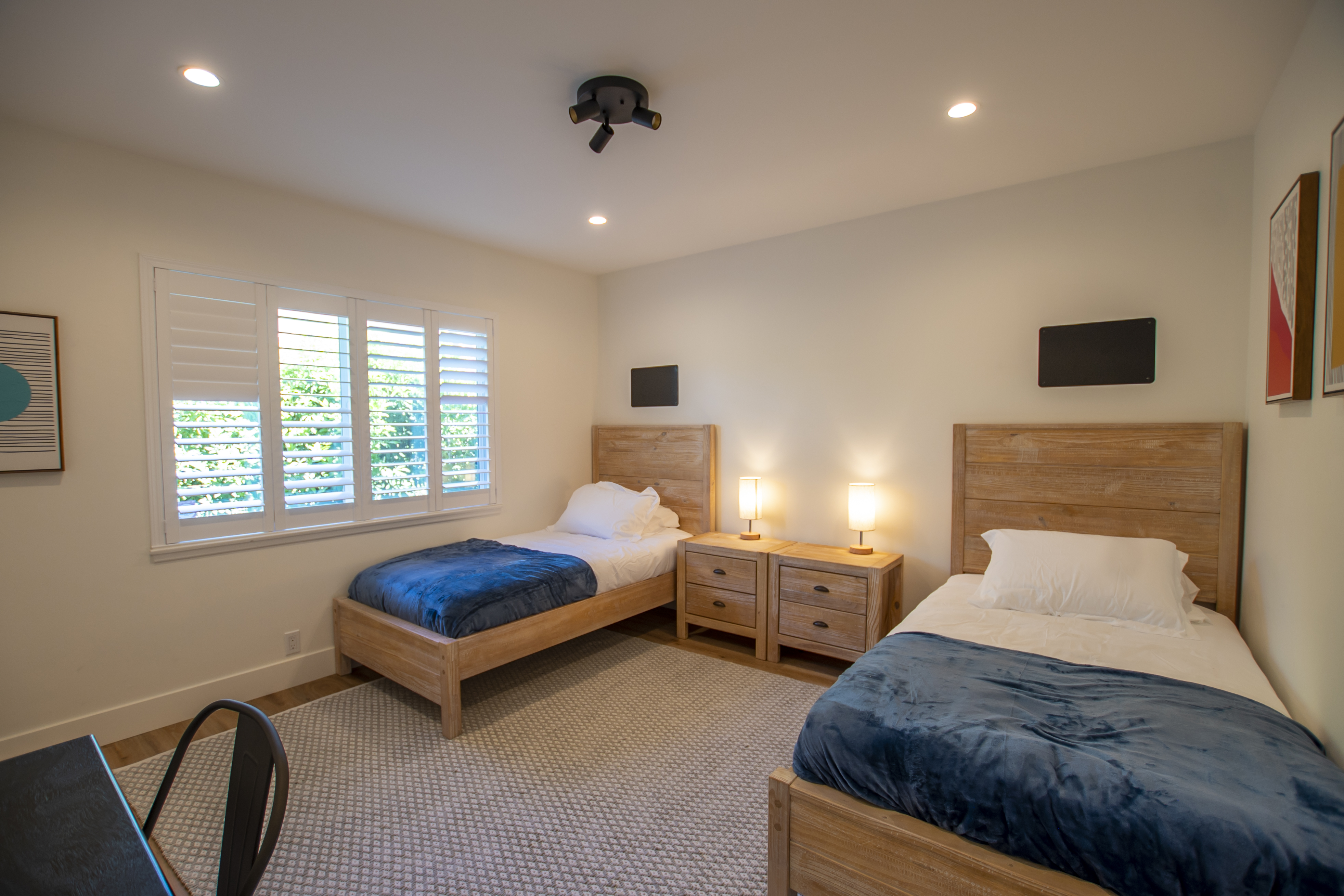 Room with two beds, blue throws, and wood furniture