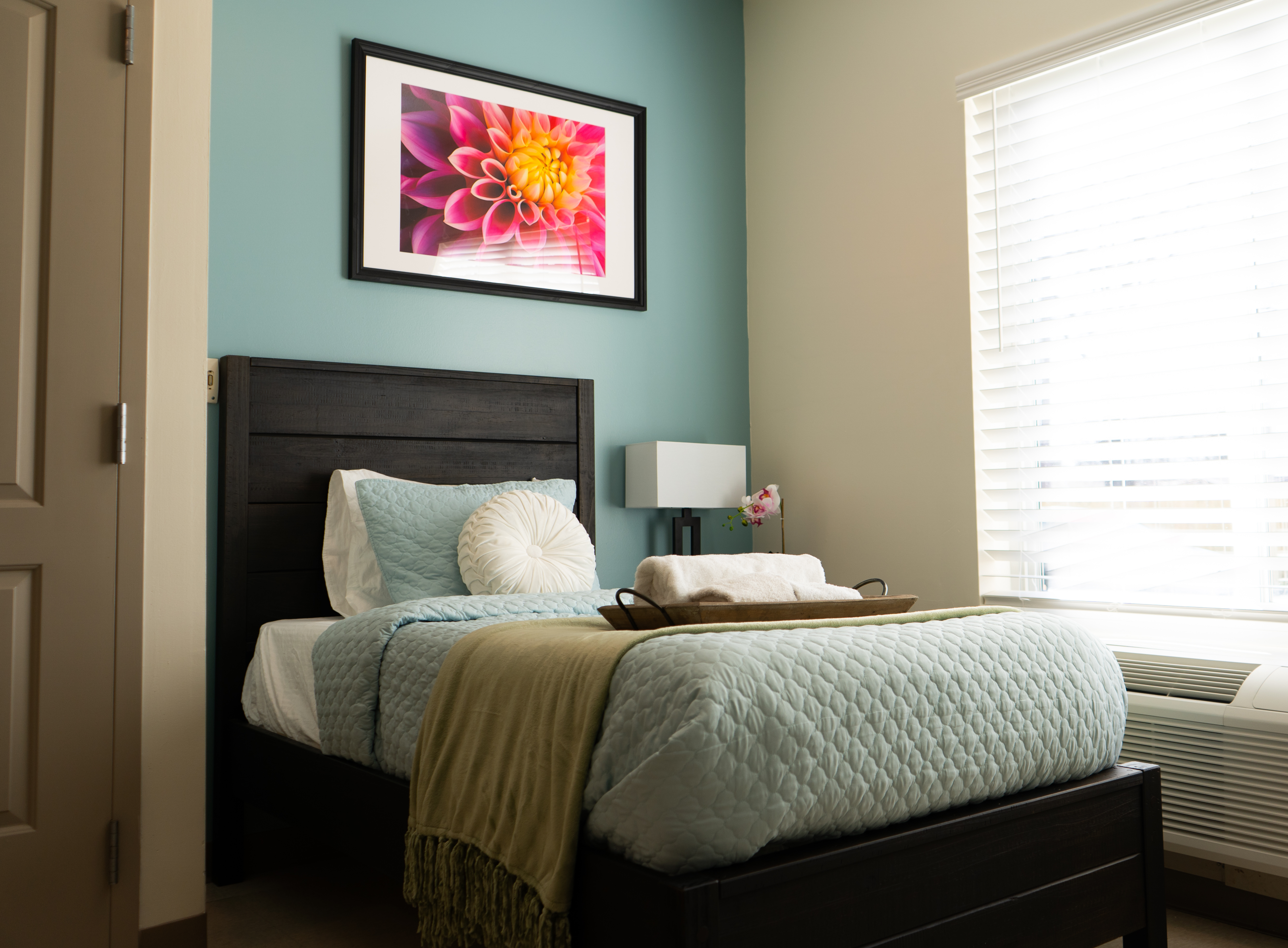 Cozy bedroom with single bed, soft bedding, and wall art.