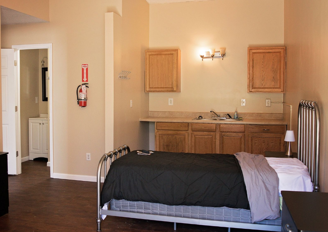 Bedroom with bed, sink, cabinets, and private bathroom