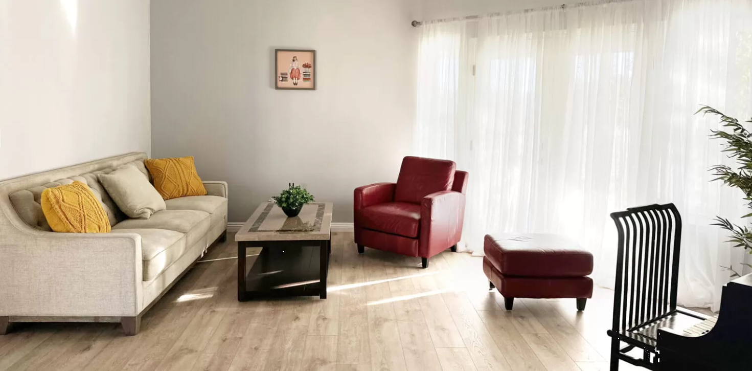 Cozy living room with beige sofa and red chairs near bright windows