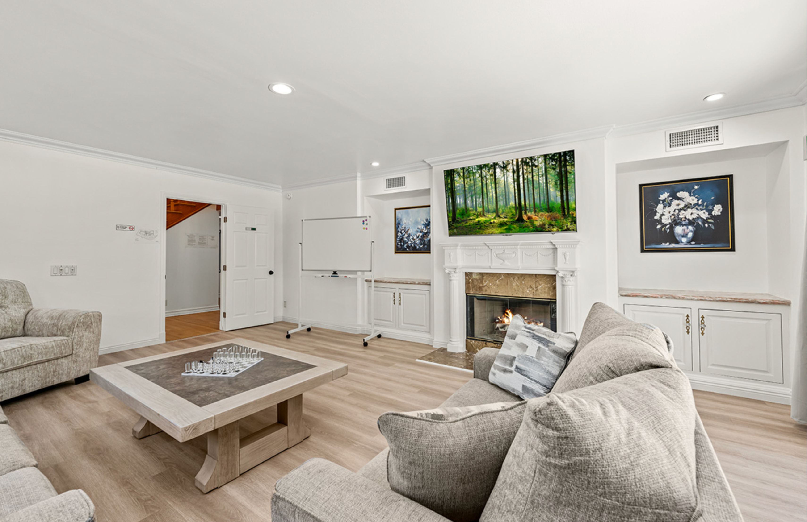 A common room with a fireplace, whiteboard, and cozy seating.