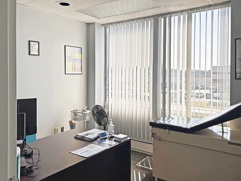 Exam room with desk, chair, and exam table by window