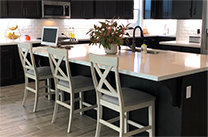 Kitchen island with white chairs and dark cabinets