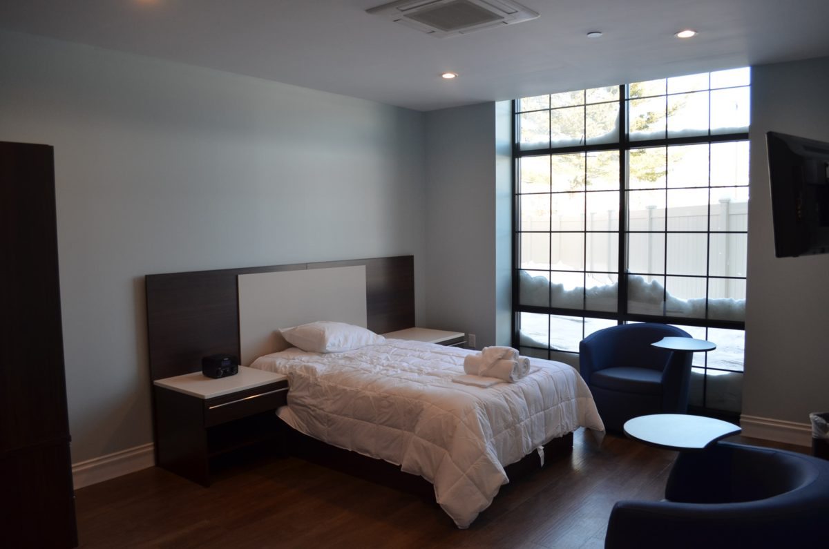 Minimalist bedroom with a large window and modern furnishings.