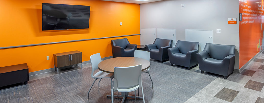 Resident lounge with seating and TV at Helio Health Elements