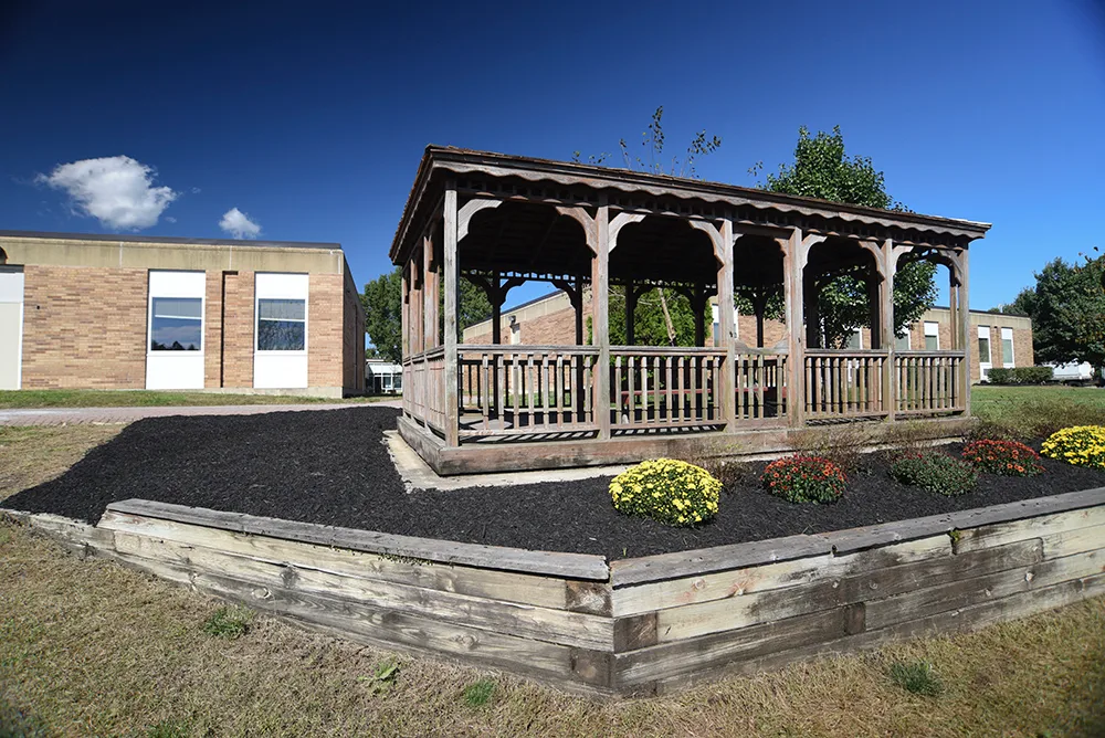 Wooden gazebo surrounded by landscaped flower beds and lawn