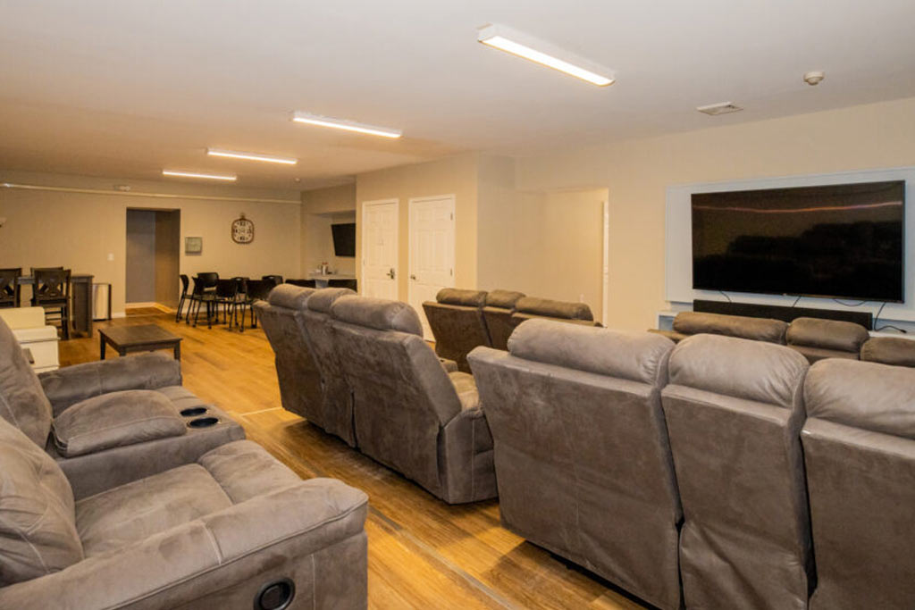 Rows of recliners facing a large TV in shared lounge