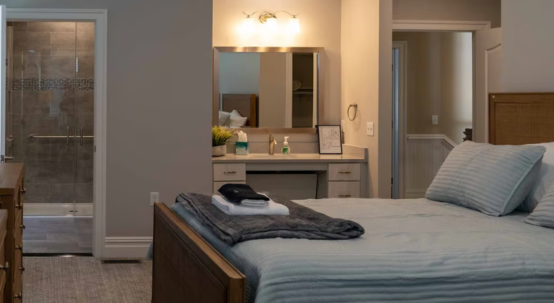Modern bedroom with gray bedding, vanity, and adjacent bathroom