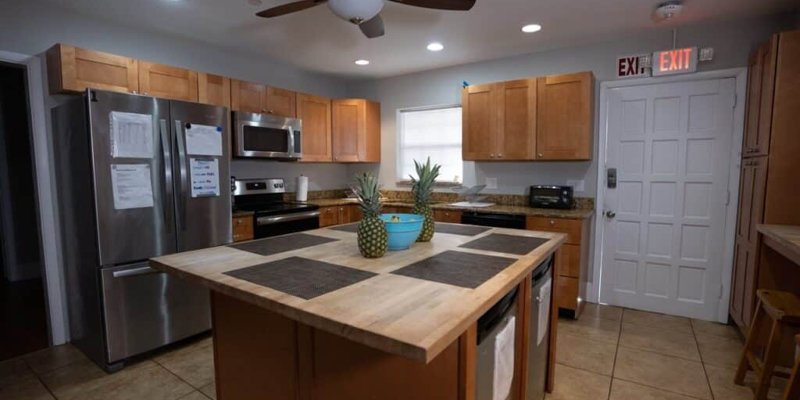  A spacious kitchen with warm wood cabinets, stainless steel appliances, and a central island, offering a functional and inviting cooking space.