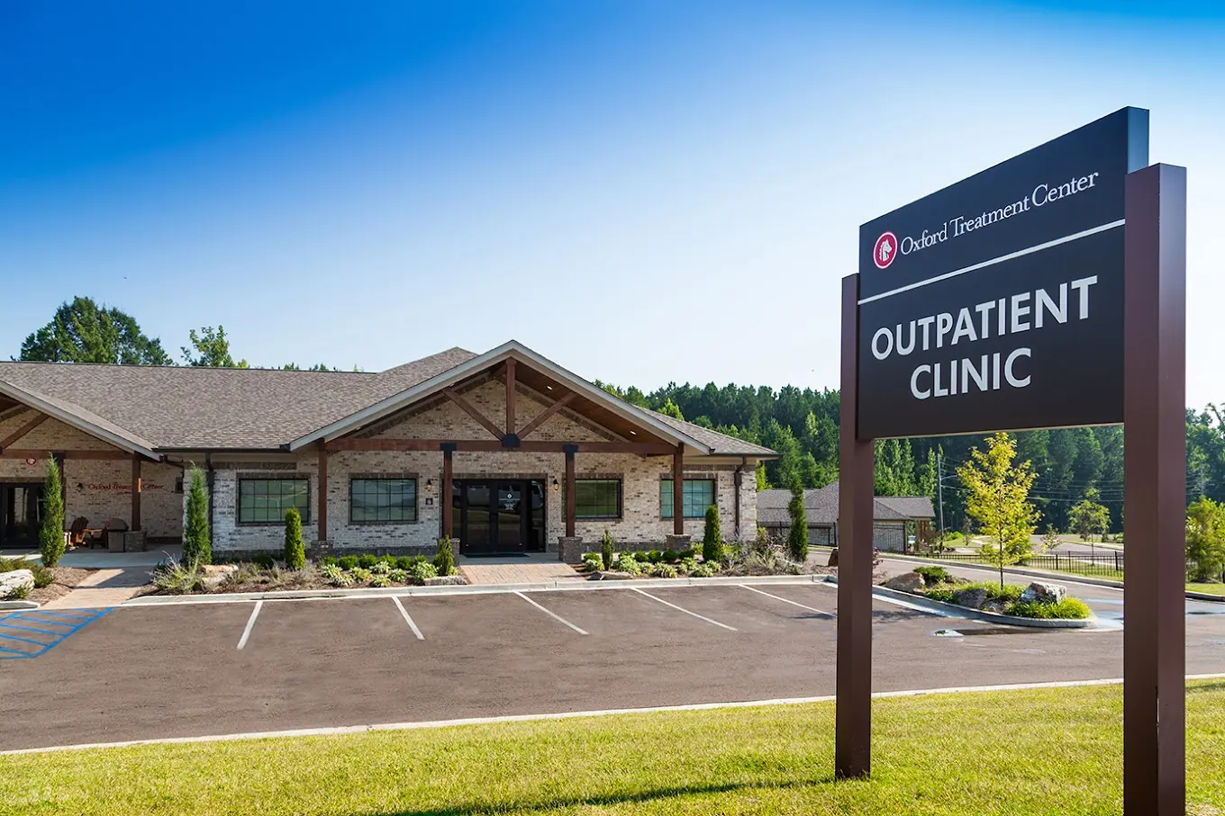 Outpatient clinic sign in front of brick building with parking lot