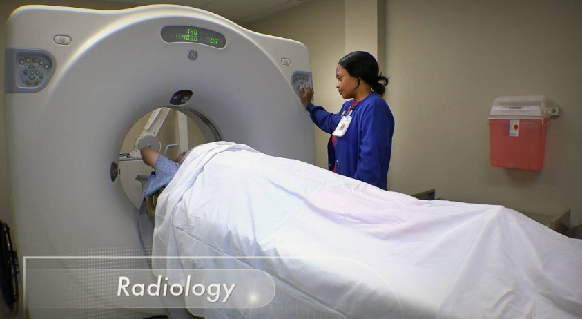 Patient in CT scanner with technician nearby