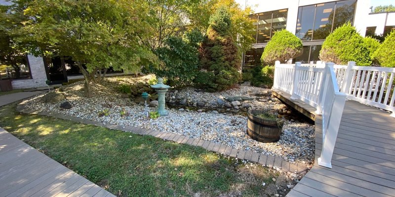 A tranquil garden area with a small stone-lined creek, surrounded by lush greenery.