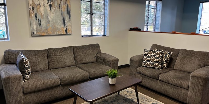 Cozy lounge area with comfortable gray sofas, patterned pillows, a modern coffee table, and abstract wall art, creating a warm and inviting atmosphere.