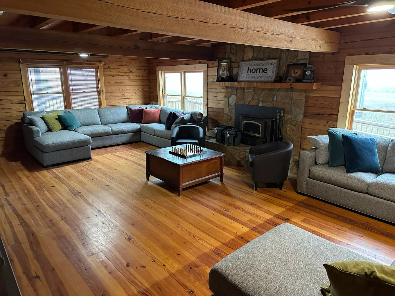 Rustic living room with sectional sofas, stone fireplace, and wood floors