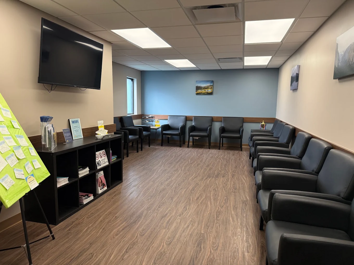 Spacious waiting room with black chairs and television