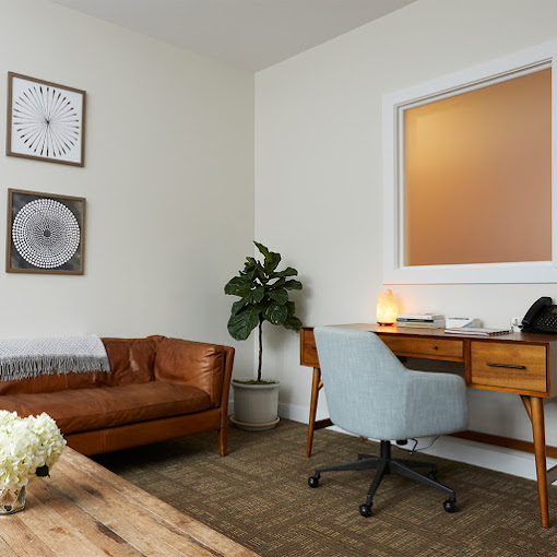 Therapy room with a couch,  desk, and a lamp.