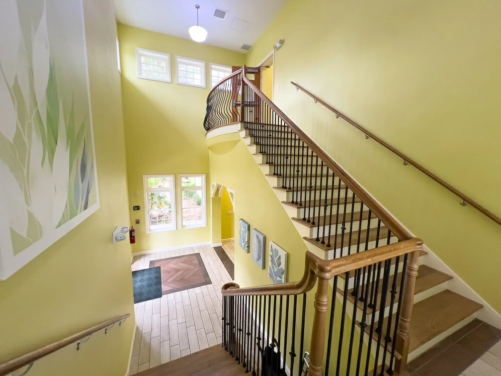Bright interior staircase with wood railings and tall windows inside residential treatment center