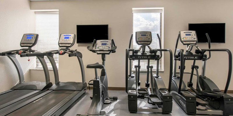 A bright fitness room featuring treadmills, exercise bikes, and ellipticals, inviting guests to stay active and maintain their wellness routine.