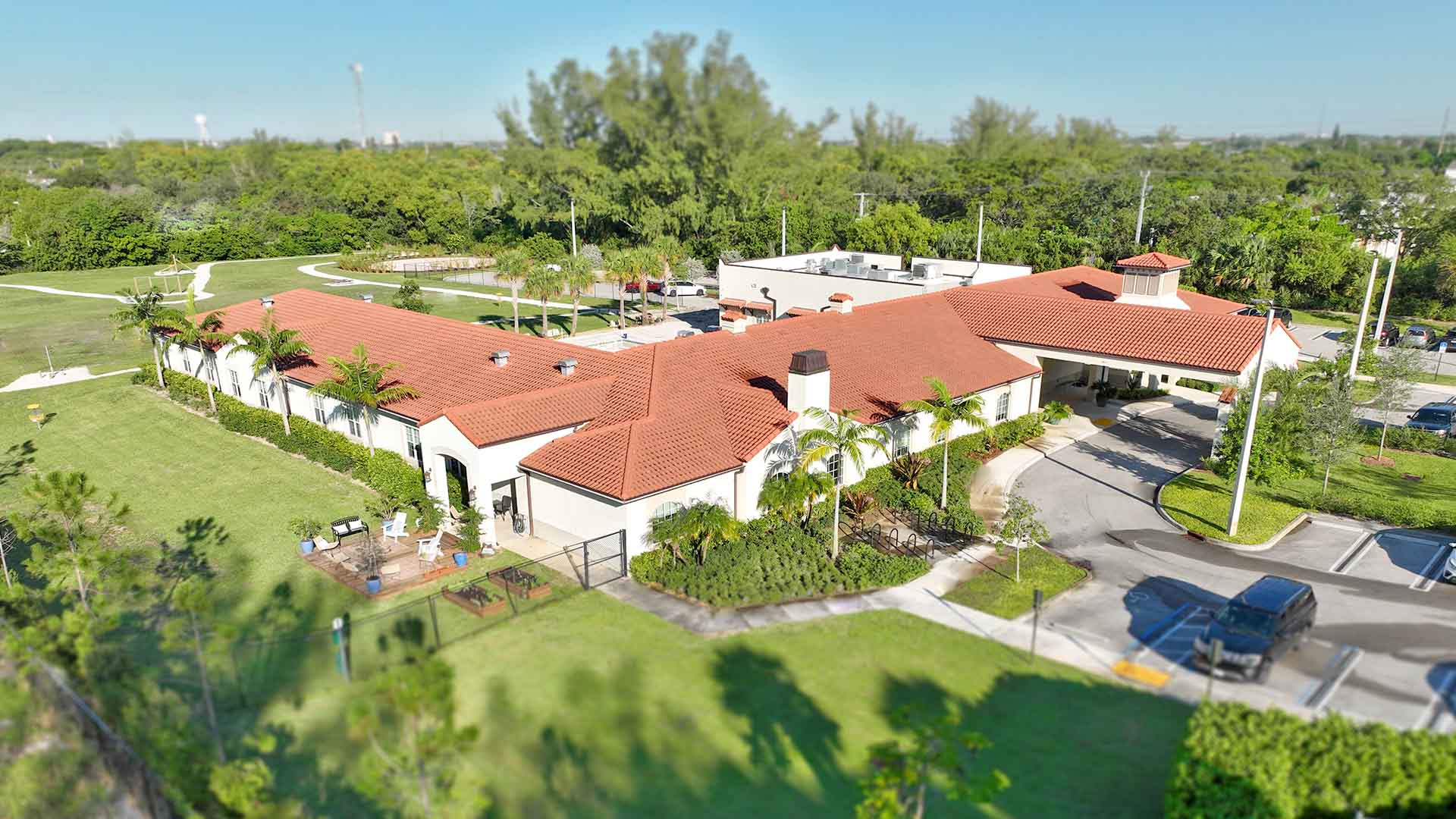Aerial view of large building with red roof and green surroundings.