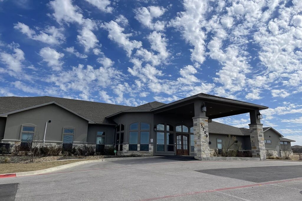 Facility exterior with large windows and accessible parking.