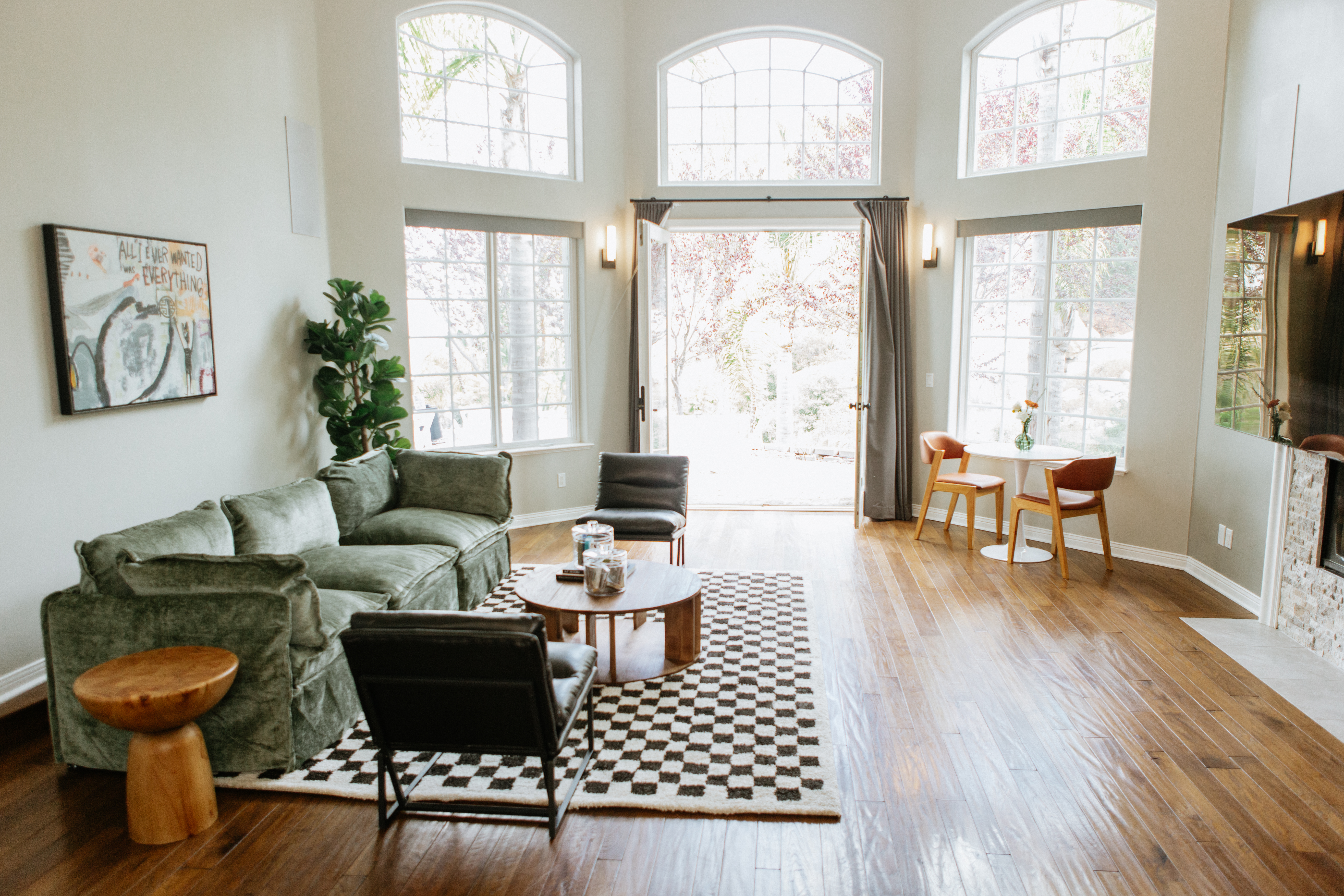 Green sofa and black chairs in room with tall windows