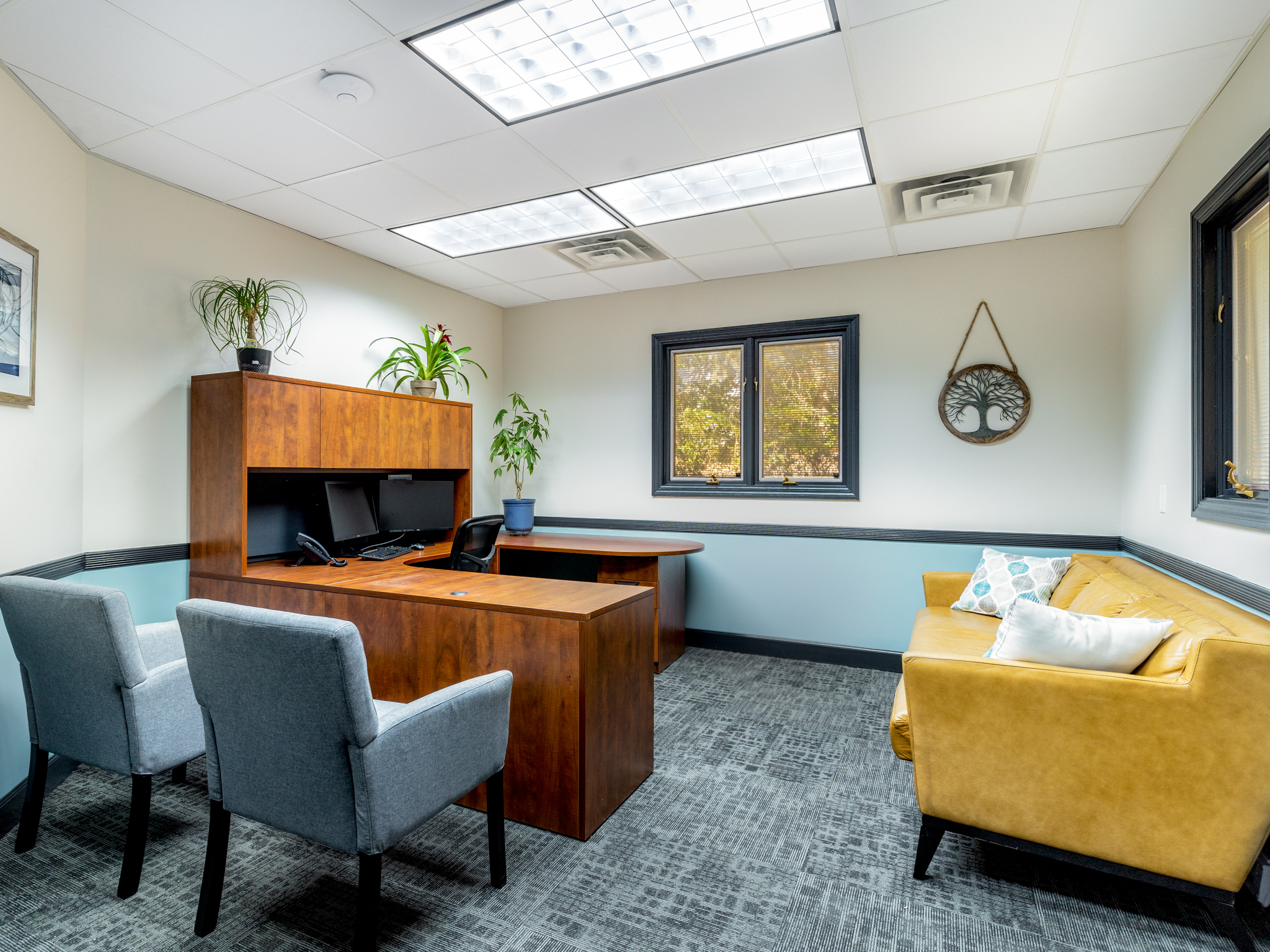 Private office with desk, chairs, and a yellow couch