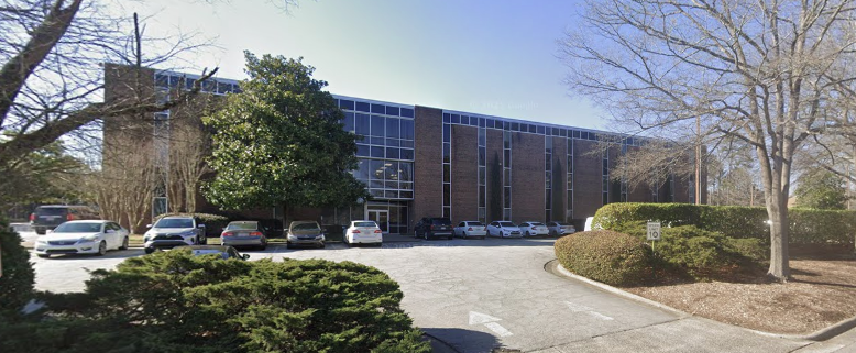 Brick building exterior with parking lot and surrounding trees