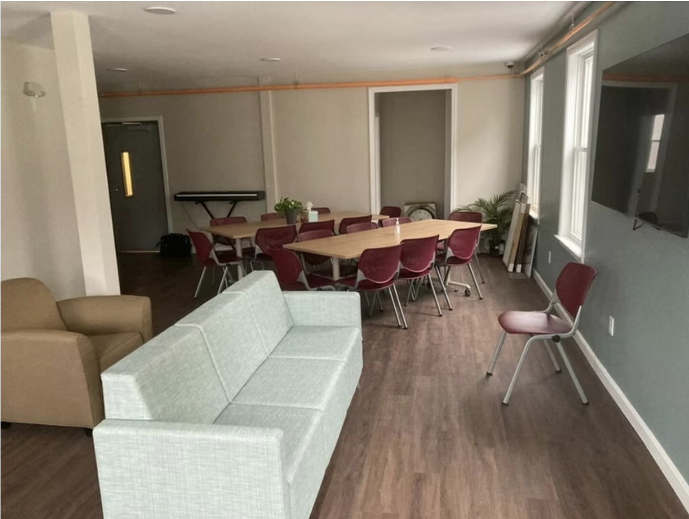 Lounge with TV, tables, and red chairs for meetings