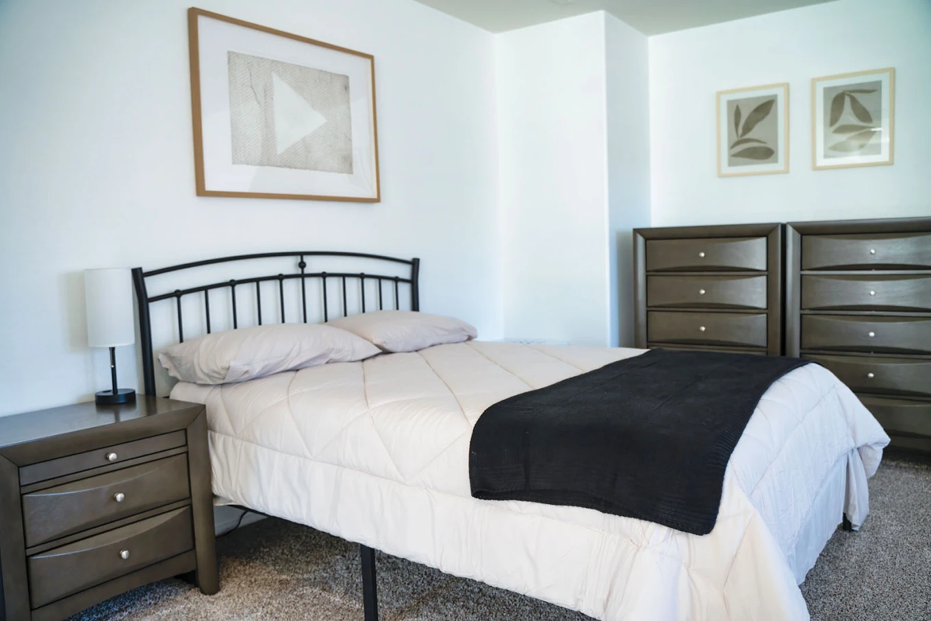 Bedroom with bed, nightstand, and dresser with wall art