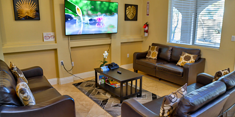 A cozy living room with leather sofas, a flat-screen TV, and a coffee table, creating a comfortable space for relaxation and entertainment.