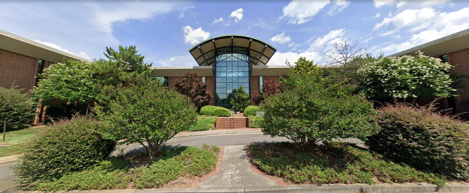 Building entrance with glass front and landscaped greenery