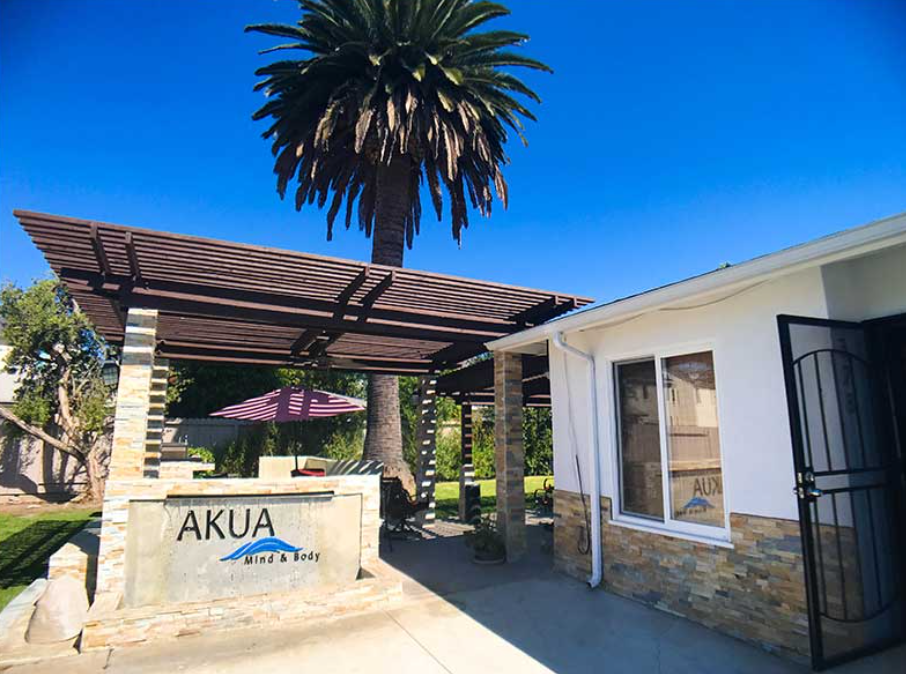 Outdoor patio with palm tree and AKUA Mind & Body sign