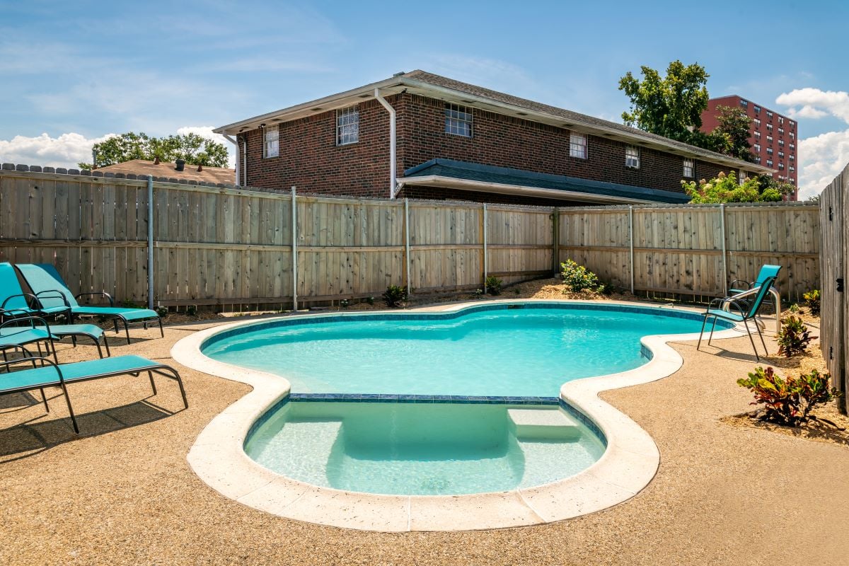 Outdoor therapy pool with lounge chairs and privacy fence.