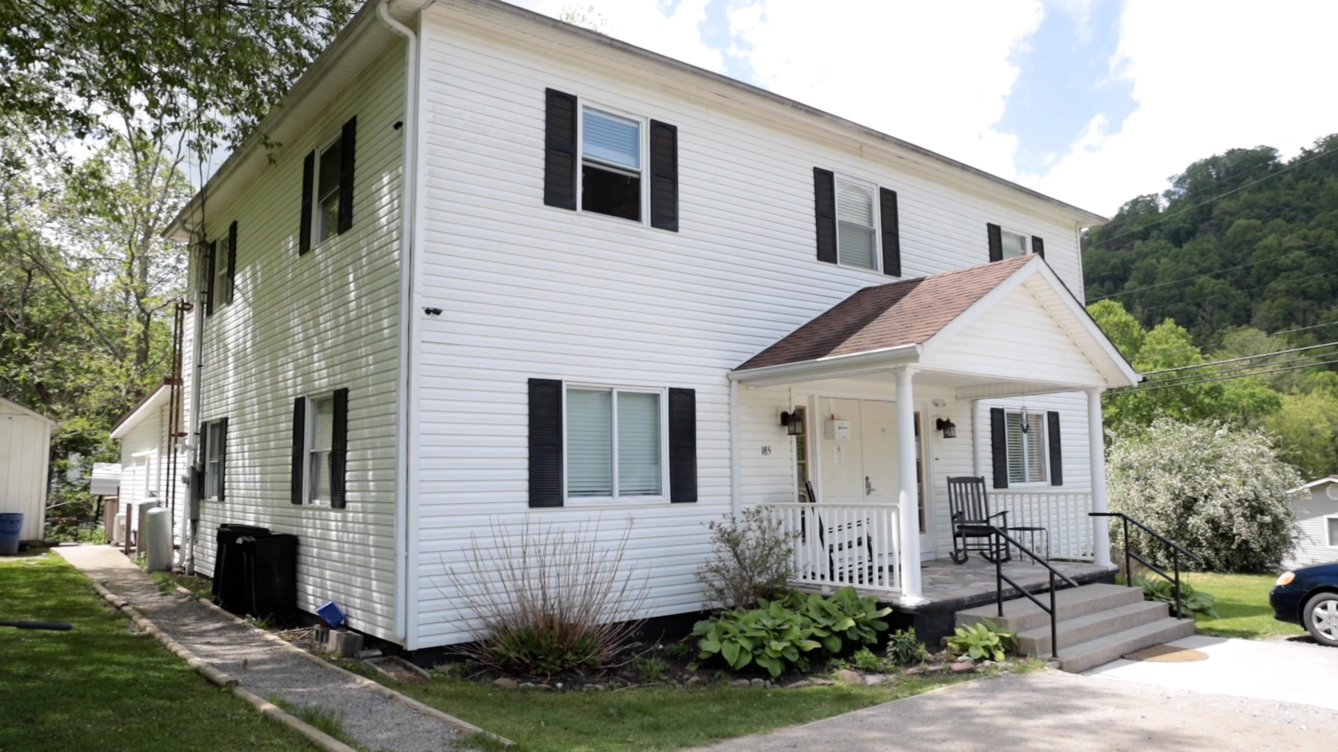 White two-story home with porch and garden