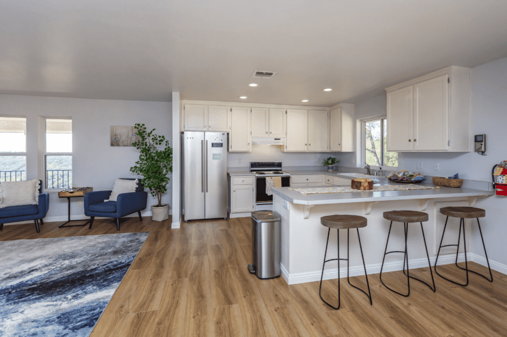 Modern kitchen with white cabinets and adjoining lounge area with seating.