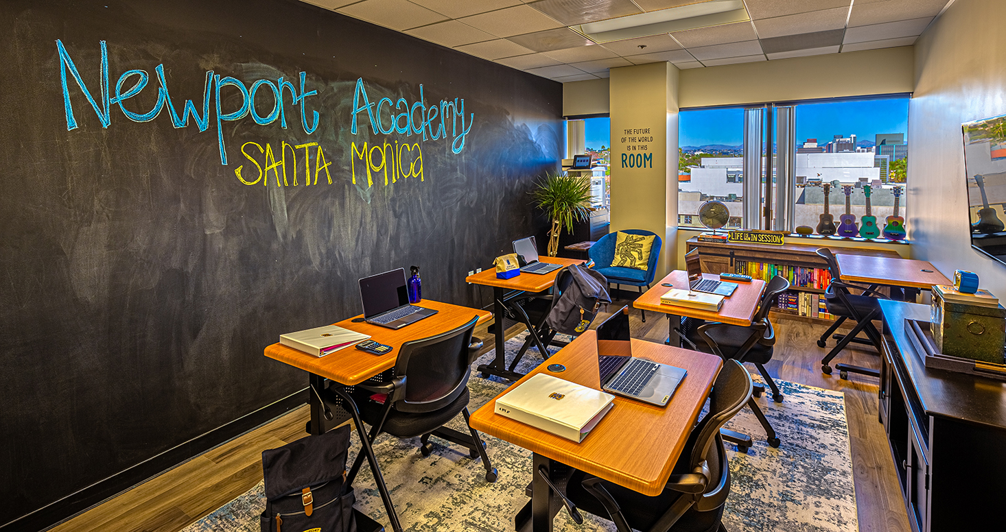 Classroom with a chalkboard wall and desks.