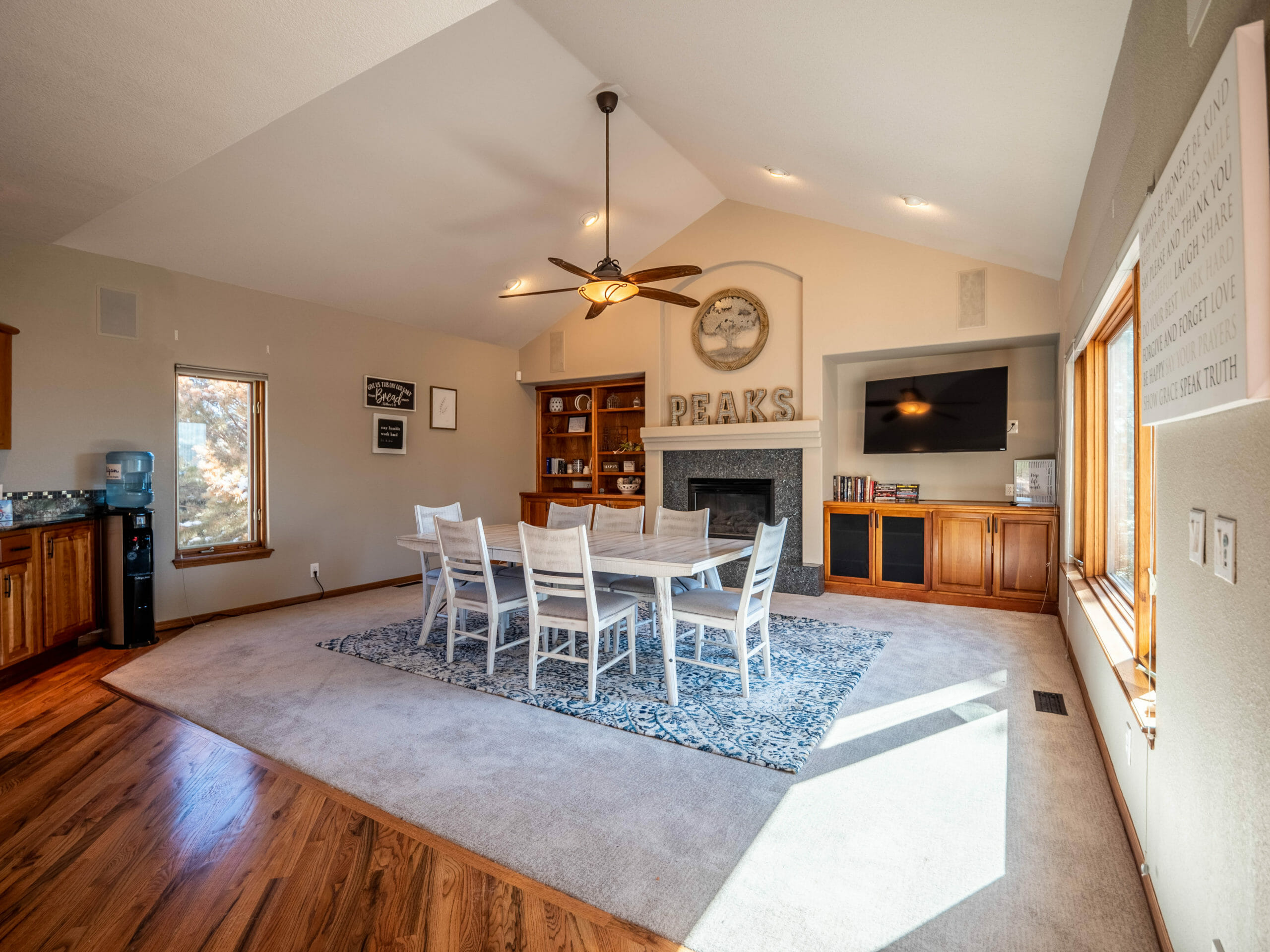 Dining area with white chairs and fireplace under vaulted ceiling