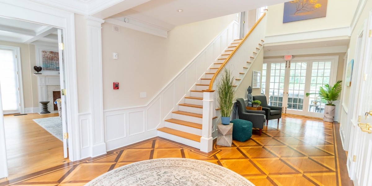 Bright lobby with staircase, seating, and wood floors